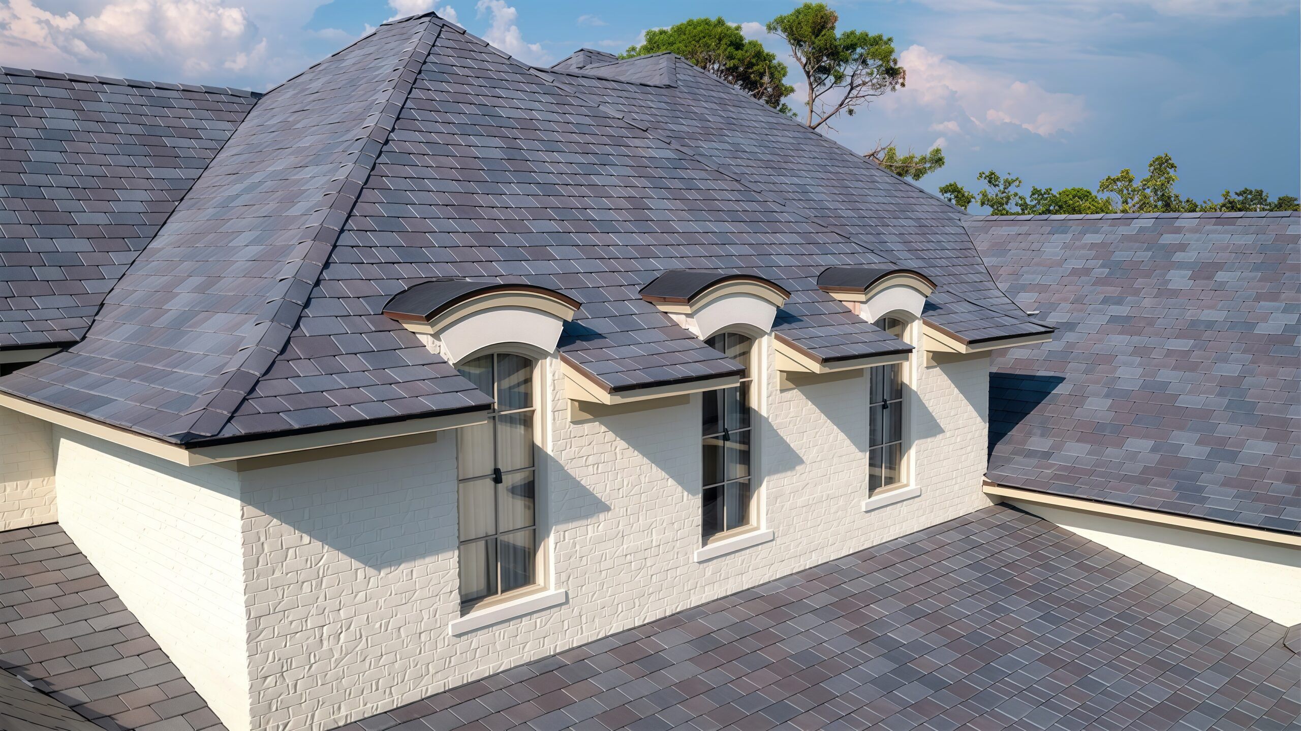 Elegant slate roof with dormer windows and brick wall below.