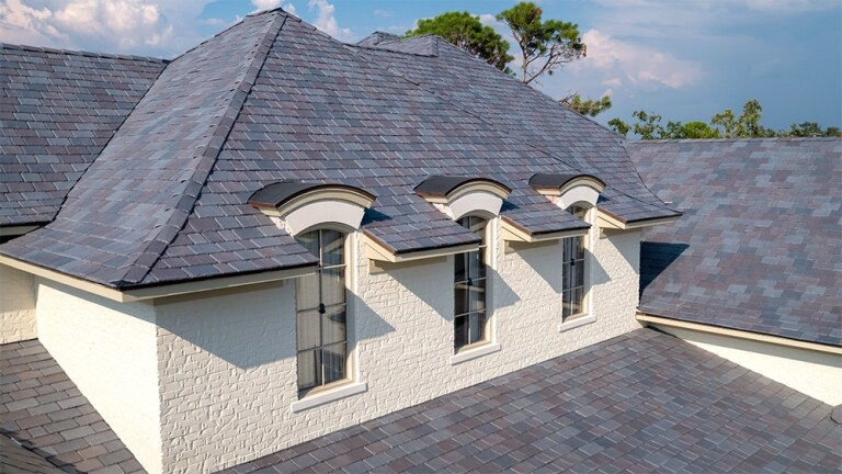 Elegant tiled roof with three arched dormers on a sunny day