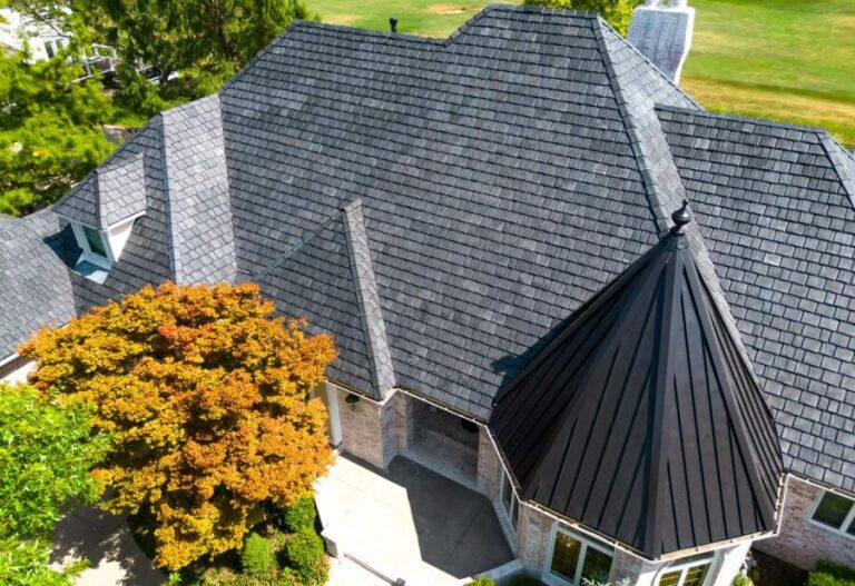Aerial view of a house with a distinctive slate roof and fall-colored trees.