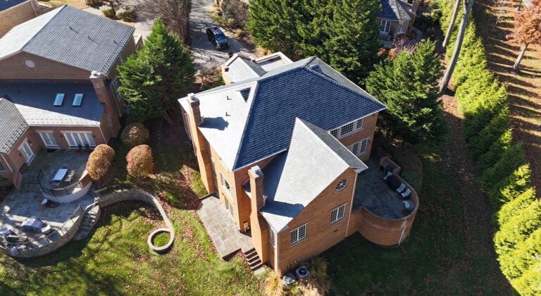 Aerial view of a large brick house with landscaped garden and driveway