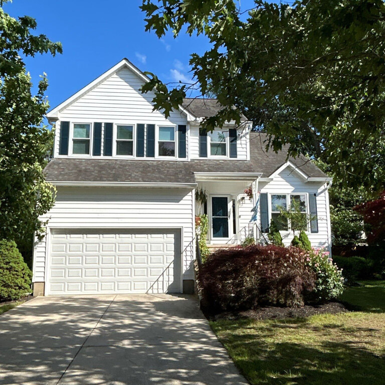 Charming two-story suburban home with garage under blue sky.