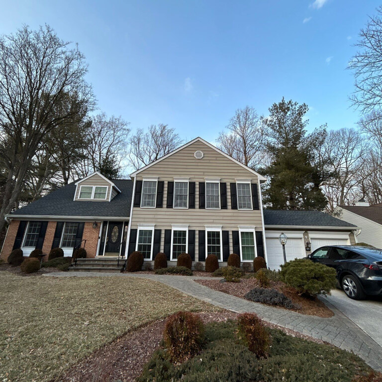 Two-story suburban house with shutters and front yard gardens