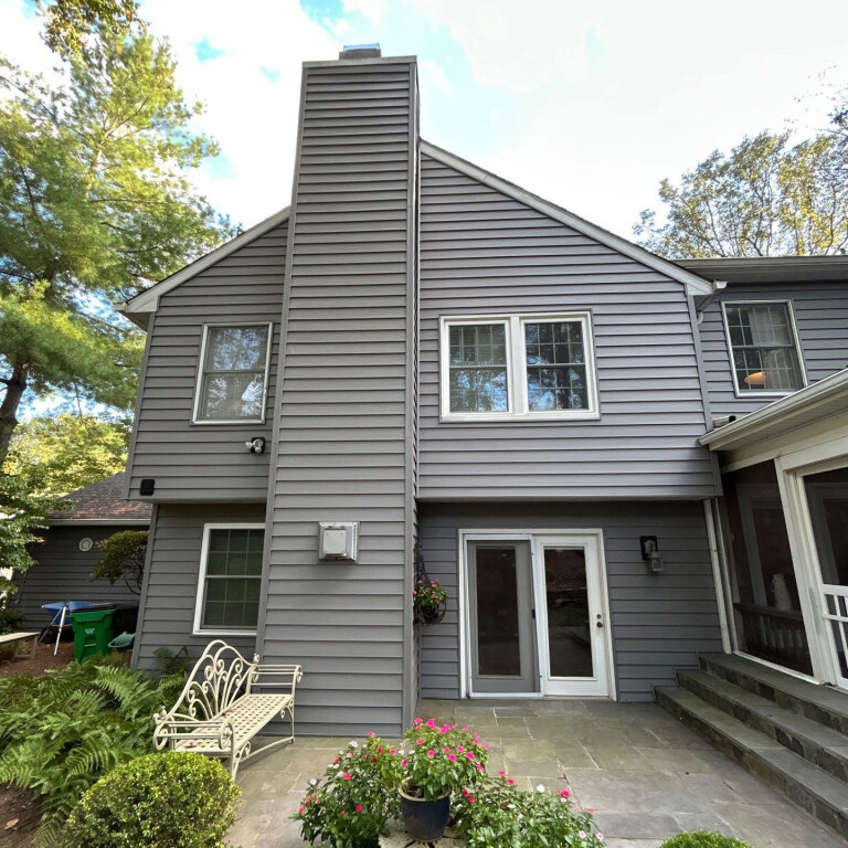 Modern two-story house with gray siding and charming garden bench