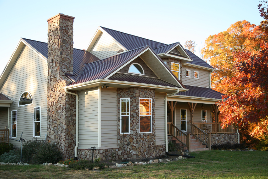 Charming two-story house with stone facade and autumn trees