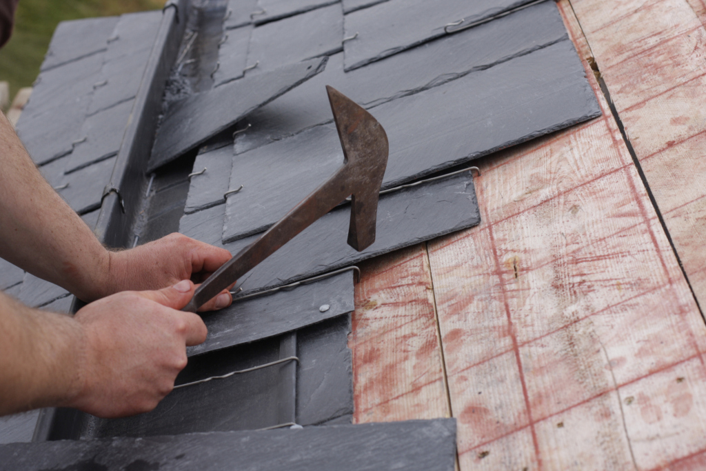 Craftsman carefully installing slate tiles on a roof