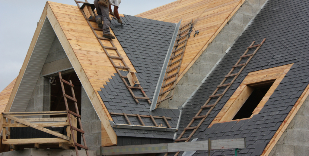 Worker installing roof shingles on a steep wooden roof structure