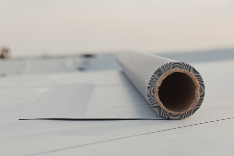 Close-up of rolled roofing material on flat rooftop.