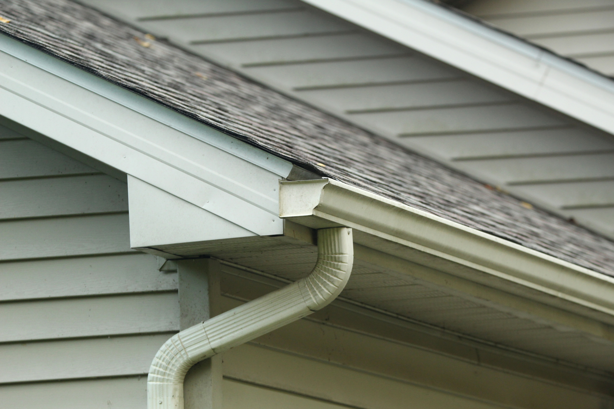 Close-up of a house roof with gutter and downspout system