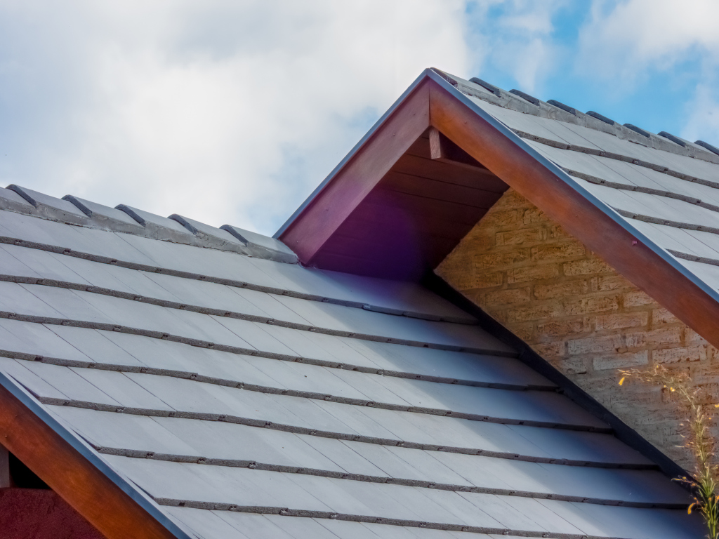 Modern house roof with gray shingles and blue sky background