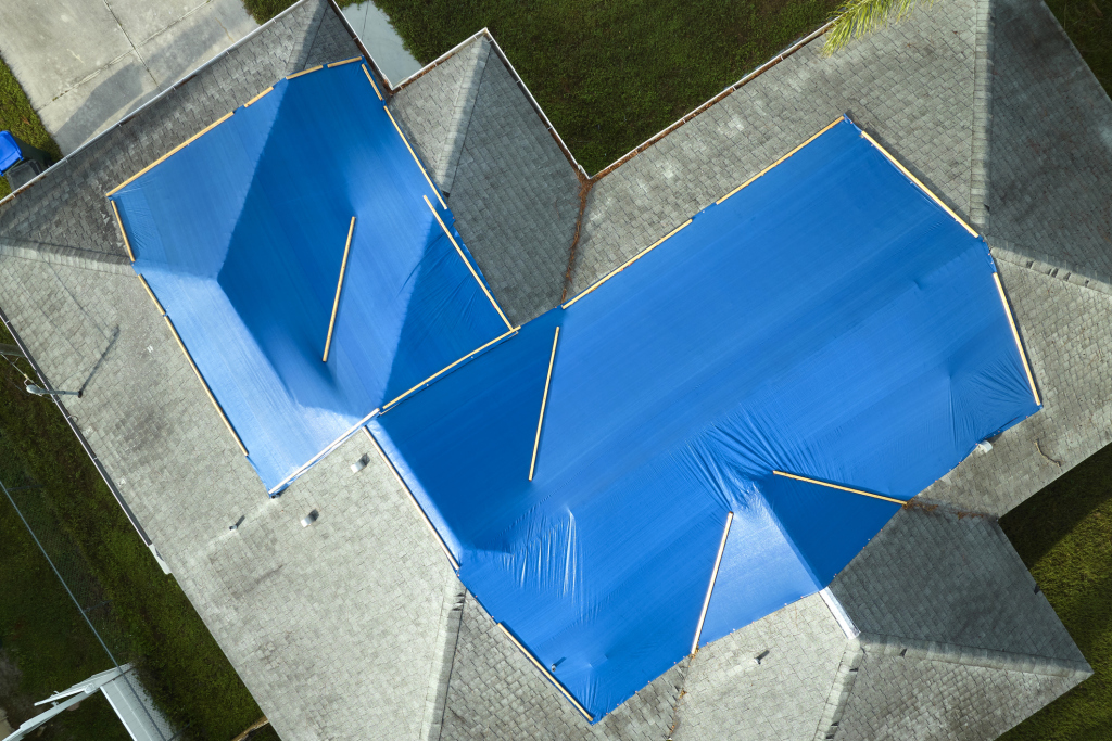 Aerial view of a roof with blue tarps for weather protection