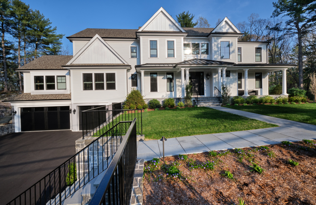 Modern white two-story house with large lawn and black garage doors