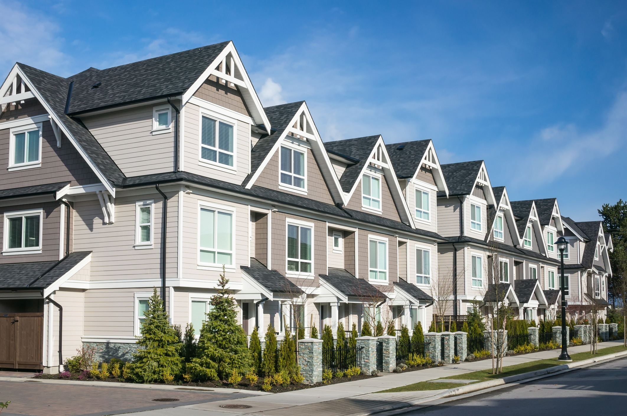 Modern row of townhouses with gabled roofs and landscaped front yards.