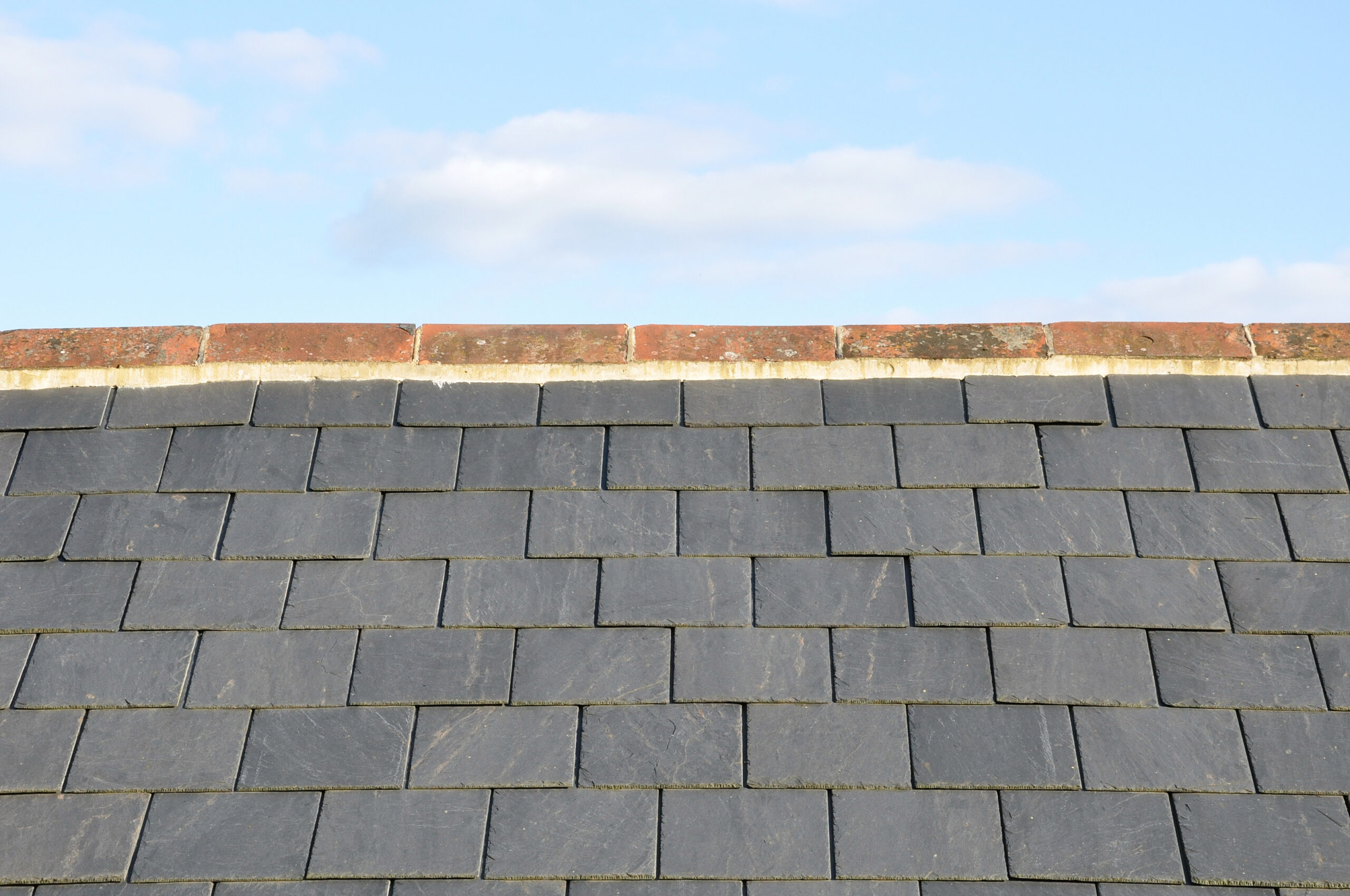 Close-up of slate roof tiles against blue sky