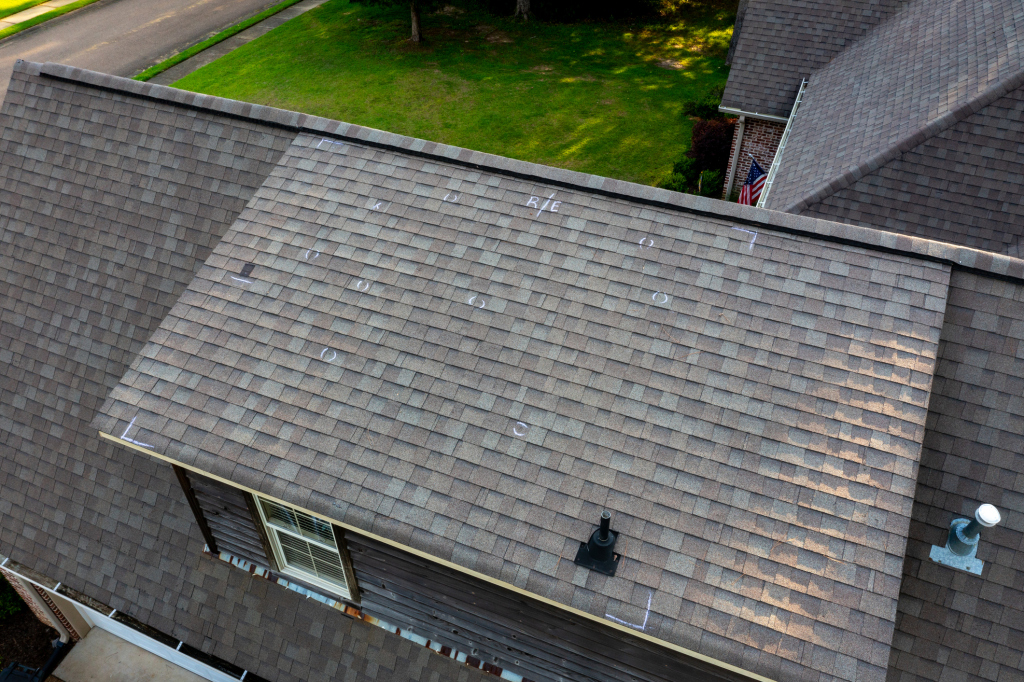 Aerial view of a residential roof with shingle damage marks.