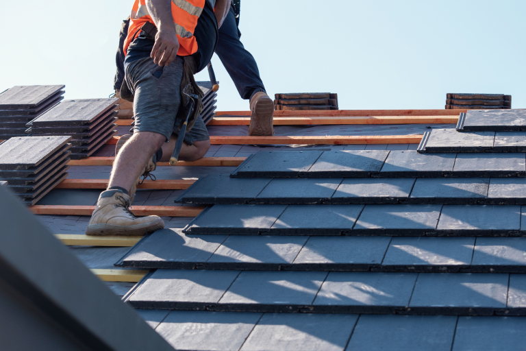 Roofers installing dark shingles on a residential rooftop