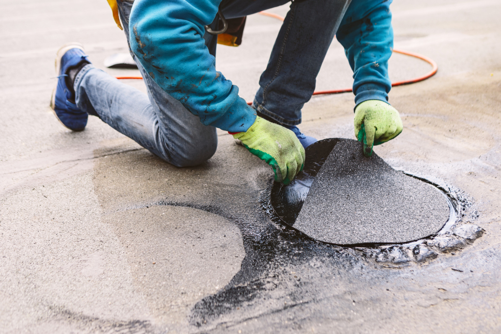 Worker repairing a pothole on asphalt road surface