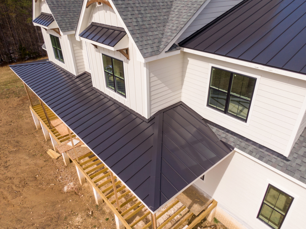 Aerial view of a modern white house with dark metal roofing.