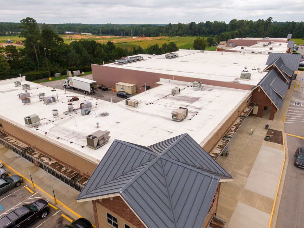 Aerial view of a large commercial building with white roofing.