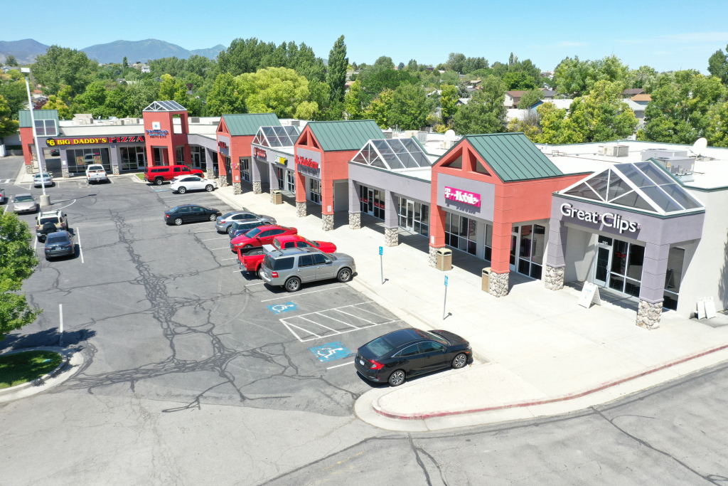 Shopping plaza with various stores including a pizzeria and salon