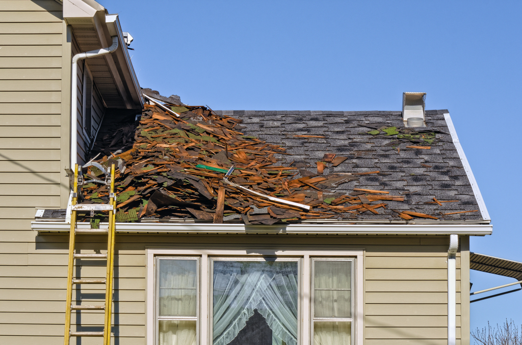Damaged roof with broken shingles and ladder on a residential house