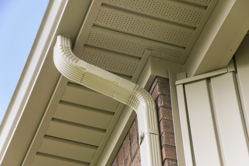 Close-up of a beige house gutter and downspout system.