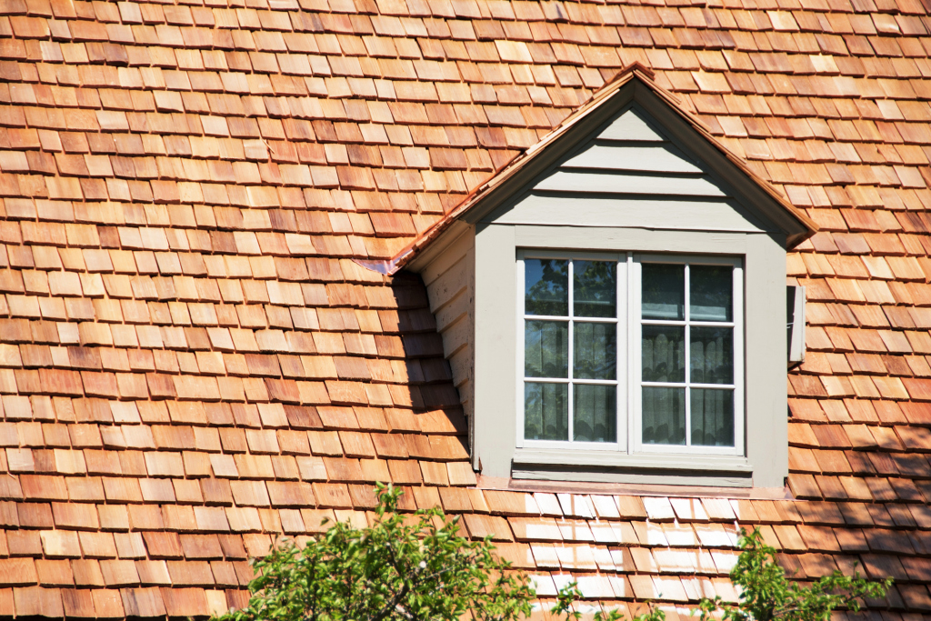 Close-up of wooden shingle roof with dormer and window in sunlight