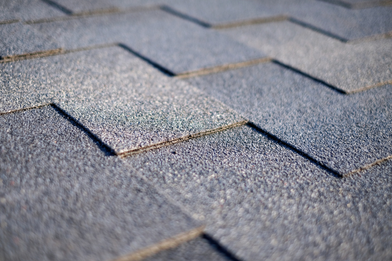 Close-up of asphalt roof shingles in sunlight.