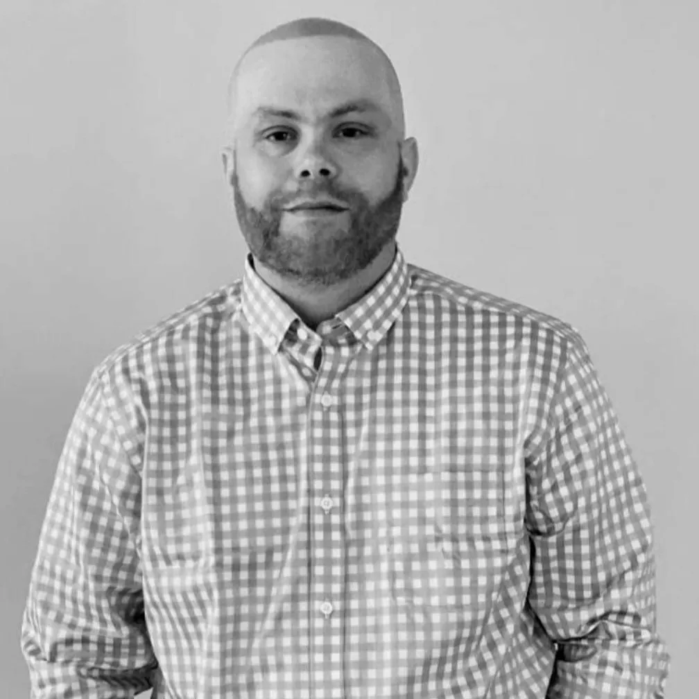 Man in checkered shirt posing against a plain background.